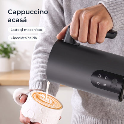 Lapte spumat turnat din spumătorul negru peste un cappuccino 