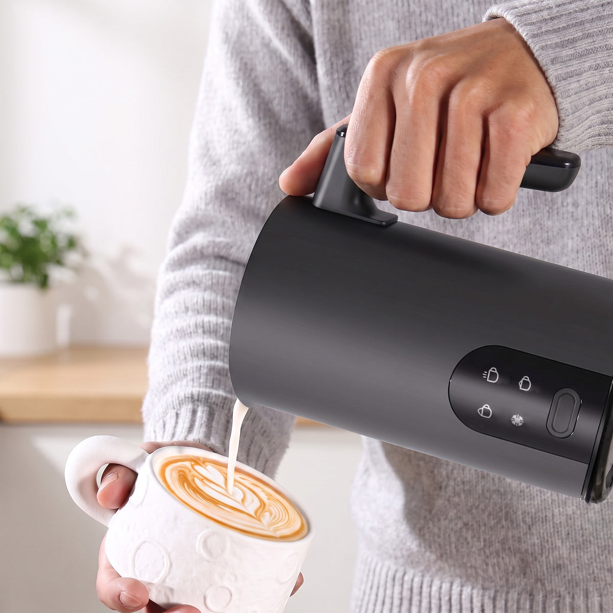 Lapte spumat turnat din spumătorul negru peste un cappuccino 
